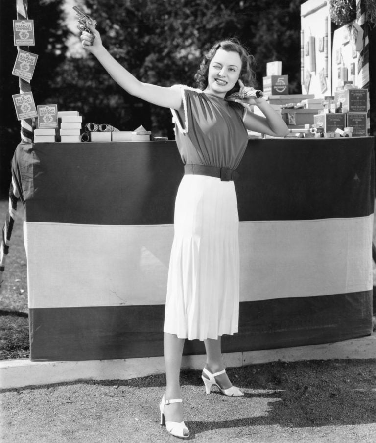 A woman shoots a gun into the air