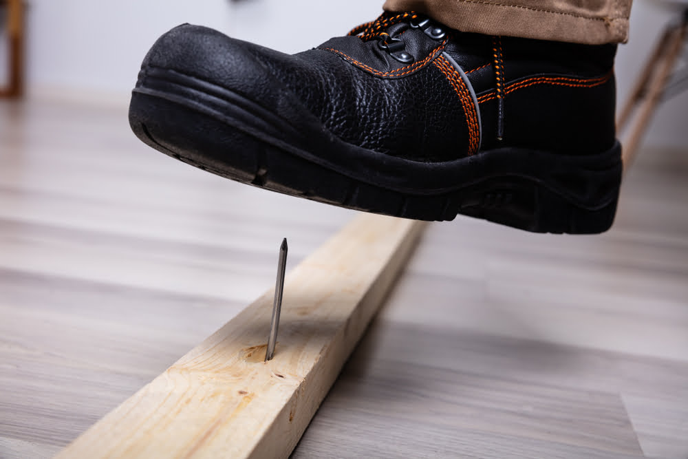 A leather boot hovering over a nail to illustrate worker's compensation fraud