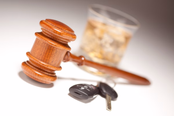 A gavel near car keys and a glass of whiskey to illustrate SR-22 after a DUI in California